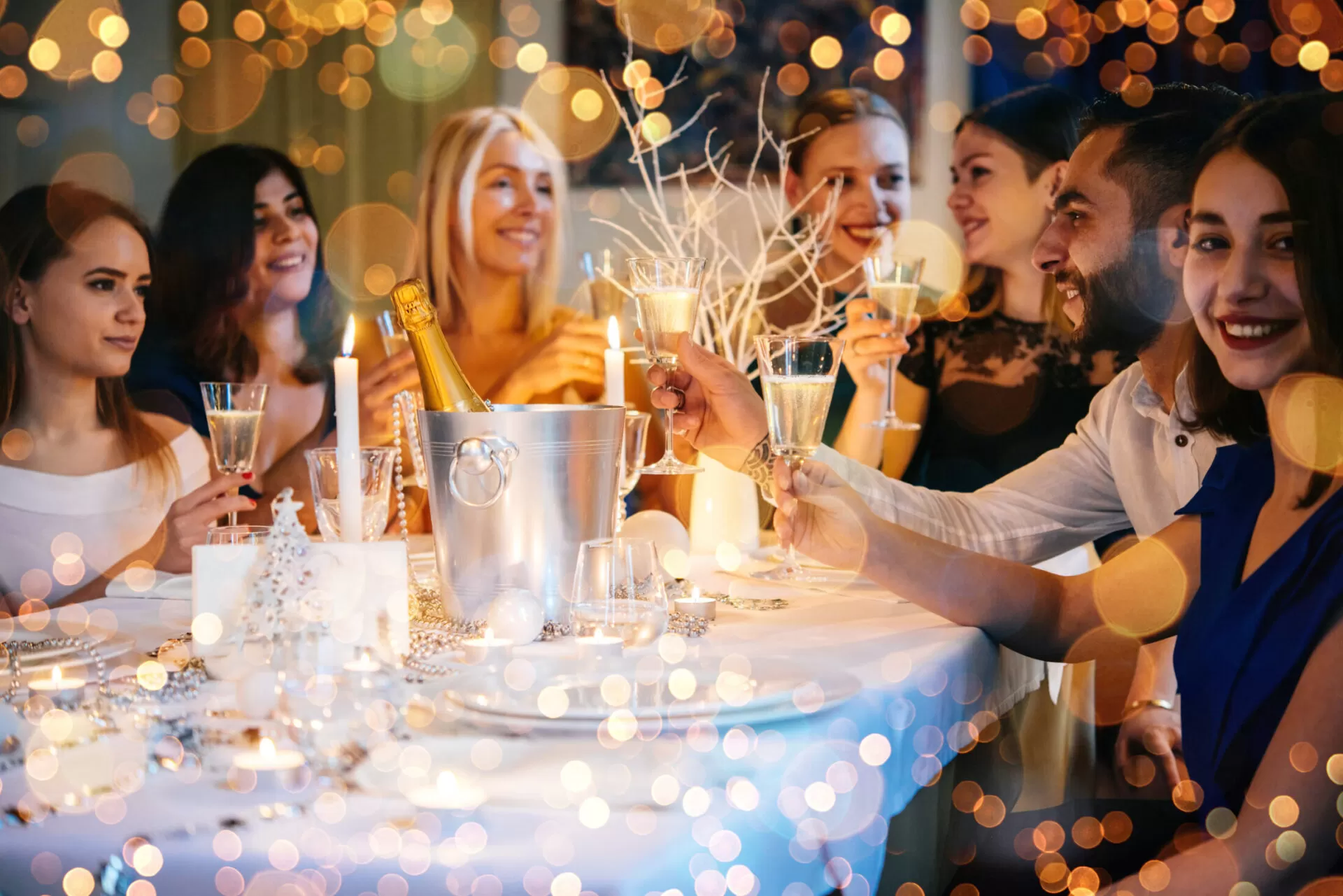 Friends celebrating Christmas or New Year eve. Party table with champagne.