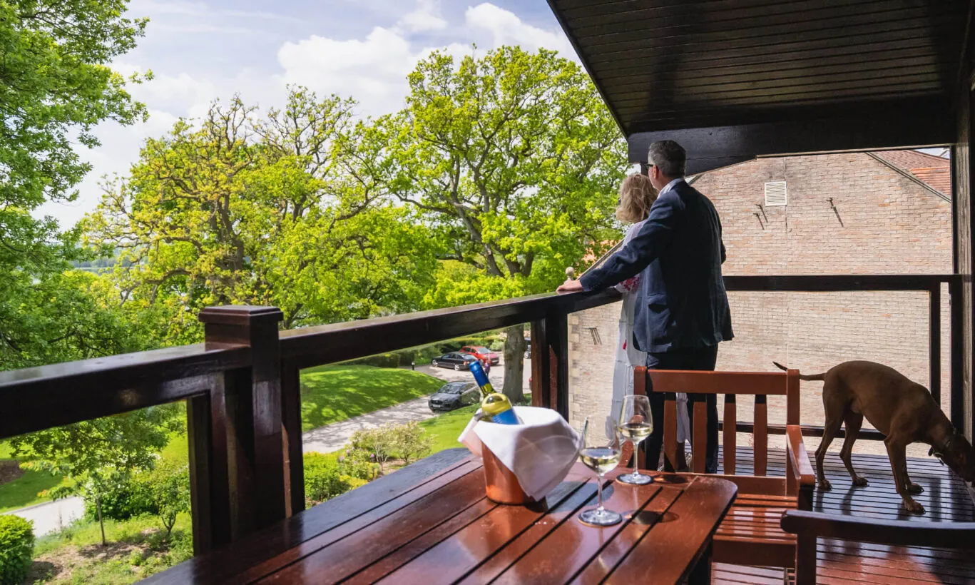Husband and wife enjoy the scenic view from their balcony at Rutland Hall Hotels & Spa